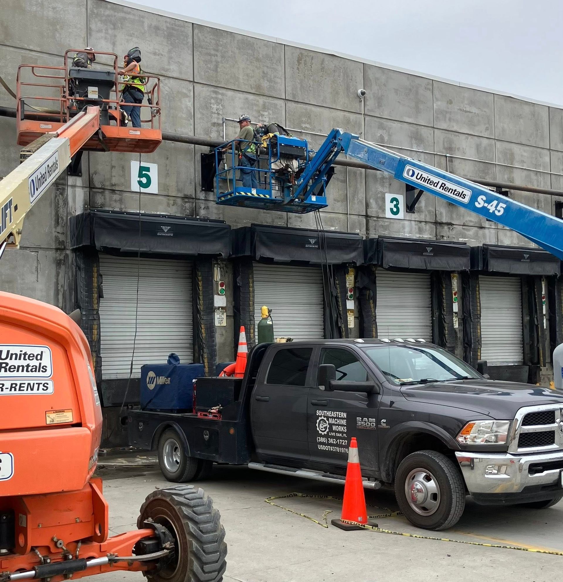 A truck is parked in front of a building with a crane on top of it.