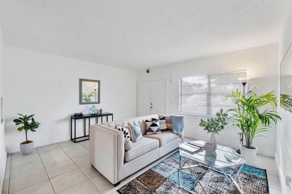 A living room with a couch , chair , coffee table and mirror.