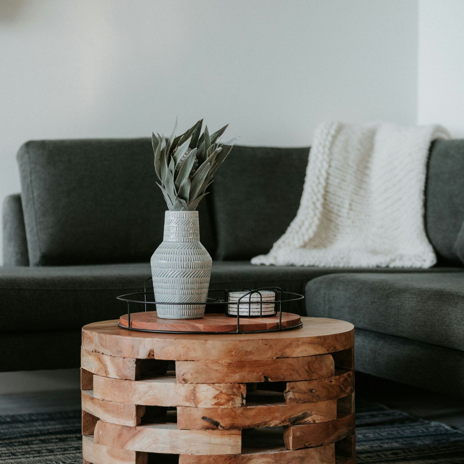 A living room with a couch and a wooden table with a vase on top of it.
