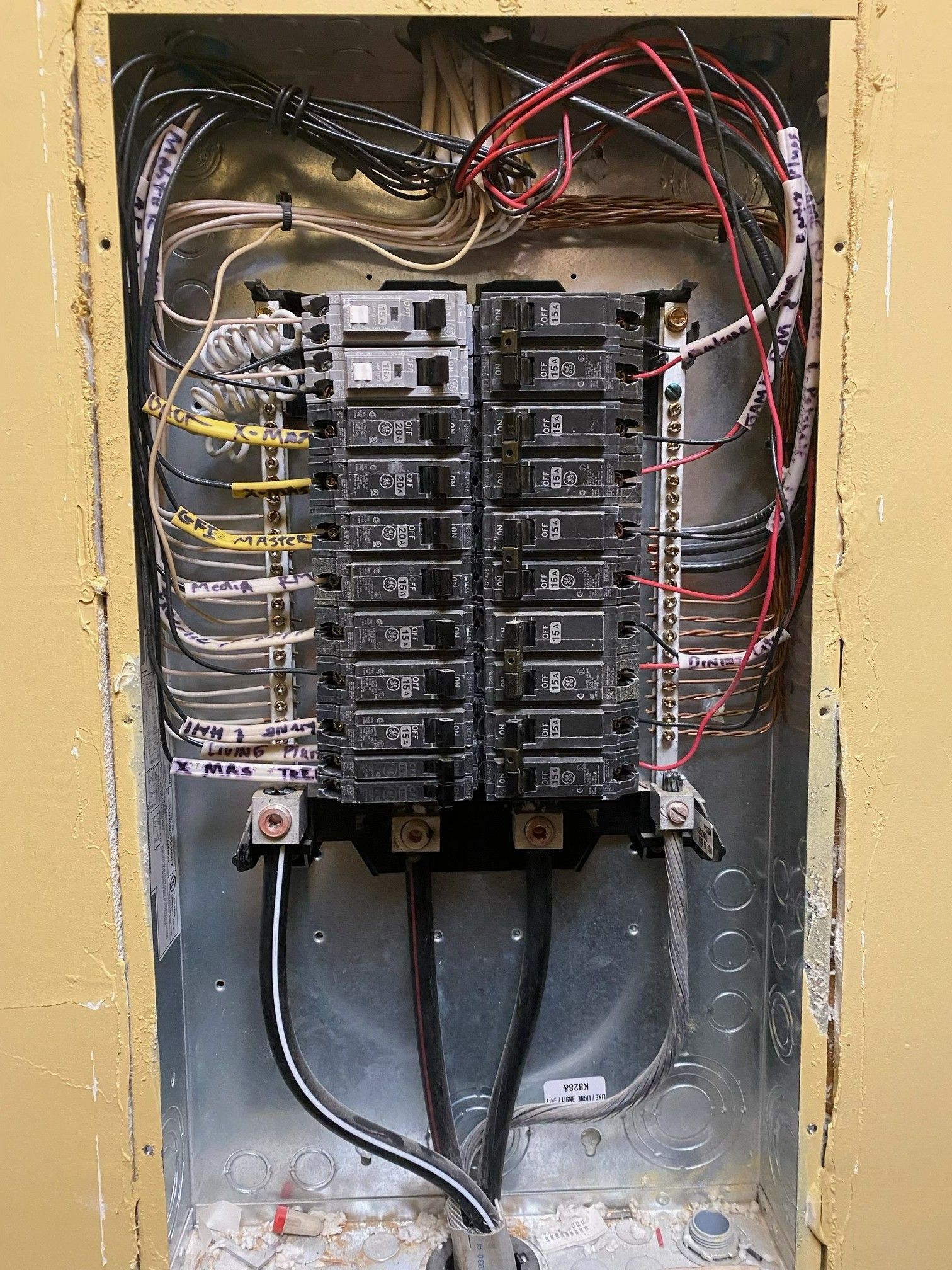 Open electrical breaker panel with exposed wiring and multiple circuit breakers inside a wall box