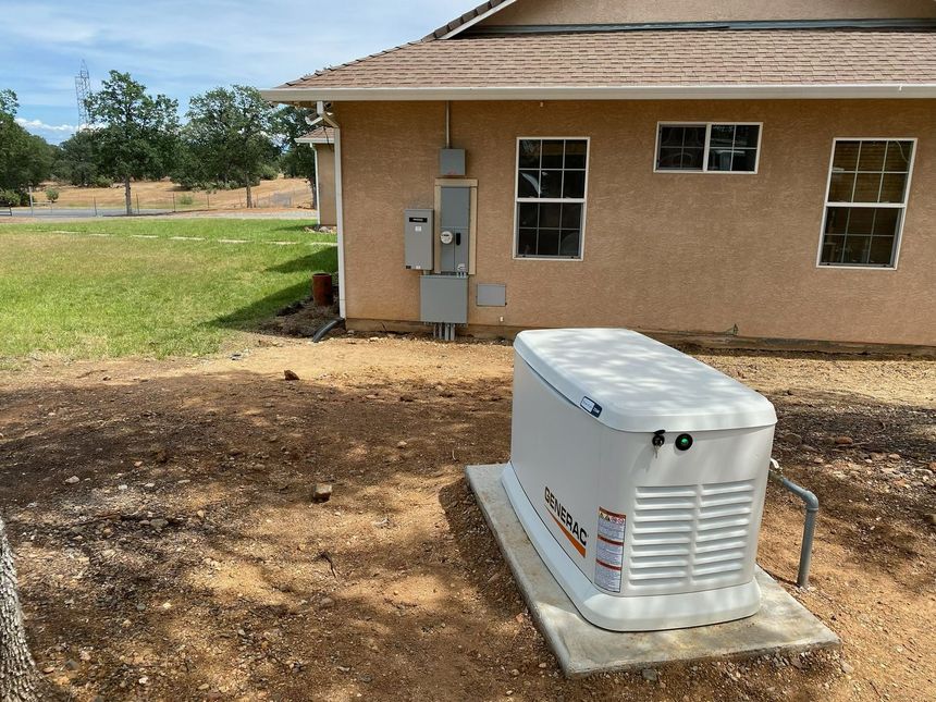 Orange industrial generator beside a gray concrete building with pipes and vents