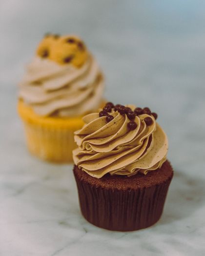 Due cupcake glassati su una superficie di marmo, uno al cioccolato e uno giallo con zuccherini