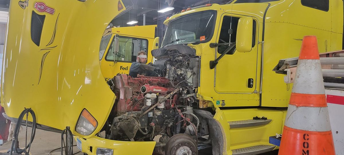 Man Fixing Yellow Vehicle - Austin, MN - Midwest Diesel Sales & Service, L.L.P.