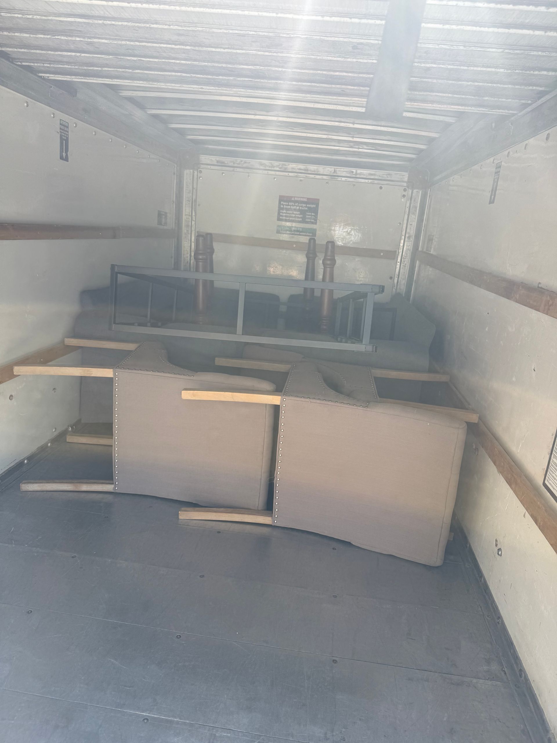 Upholstered furniture secured with wooden planks inside a moving truck.