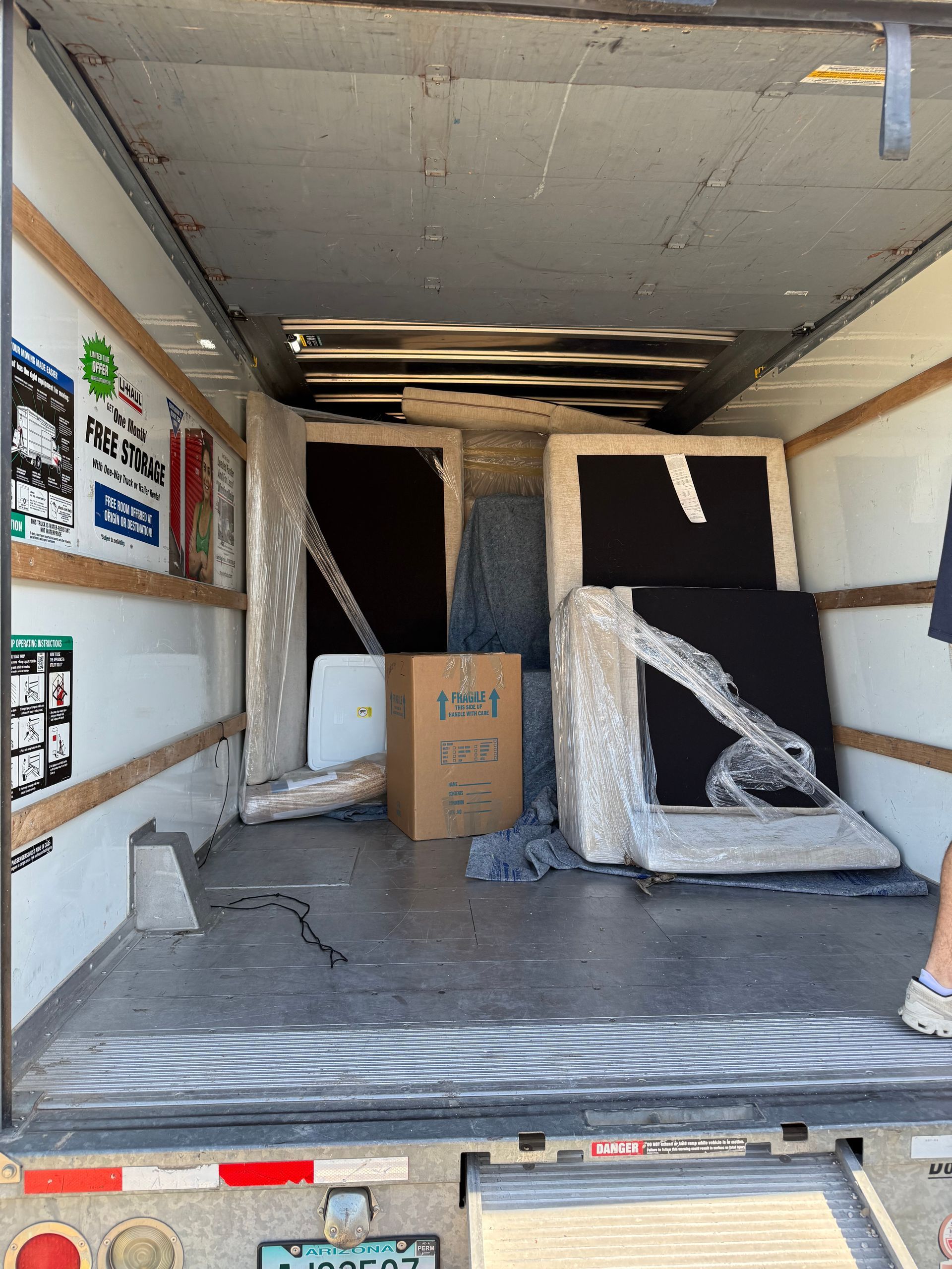 Interior of a moving truck loaded with wrapped furniture and boxes.