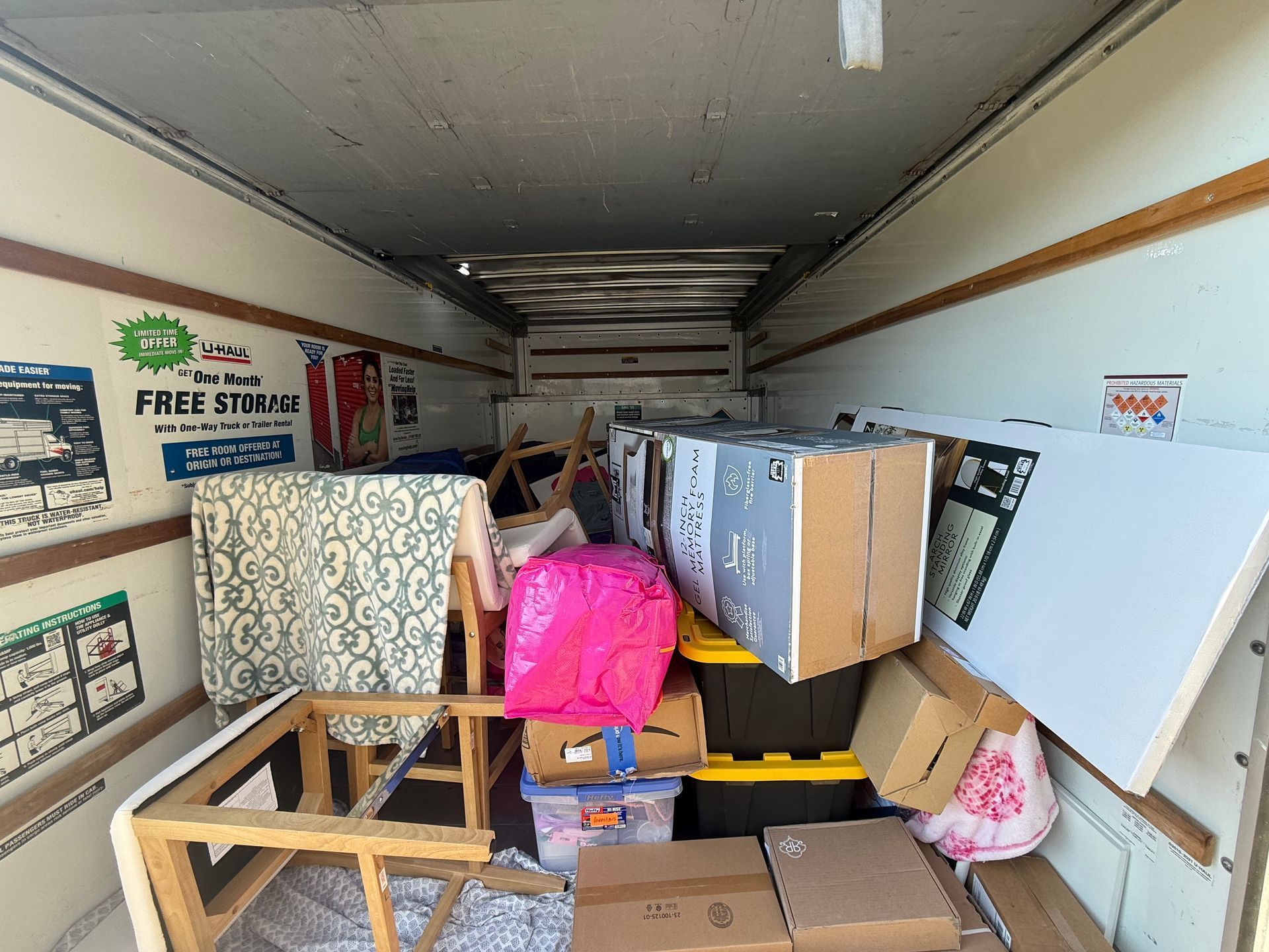 Inside of a moving truck, filled with furniture, boxes, and household items.