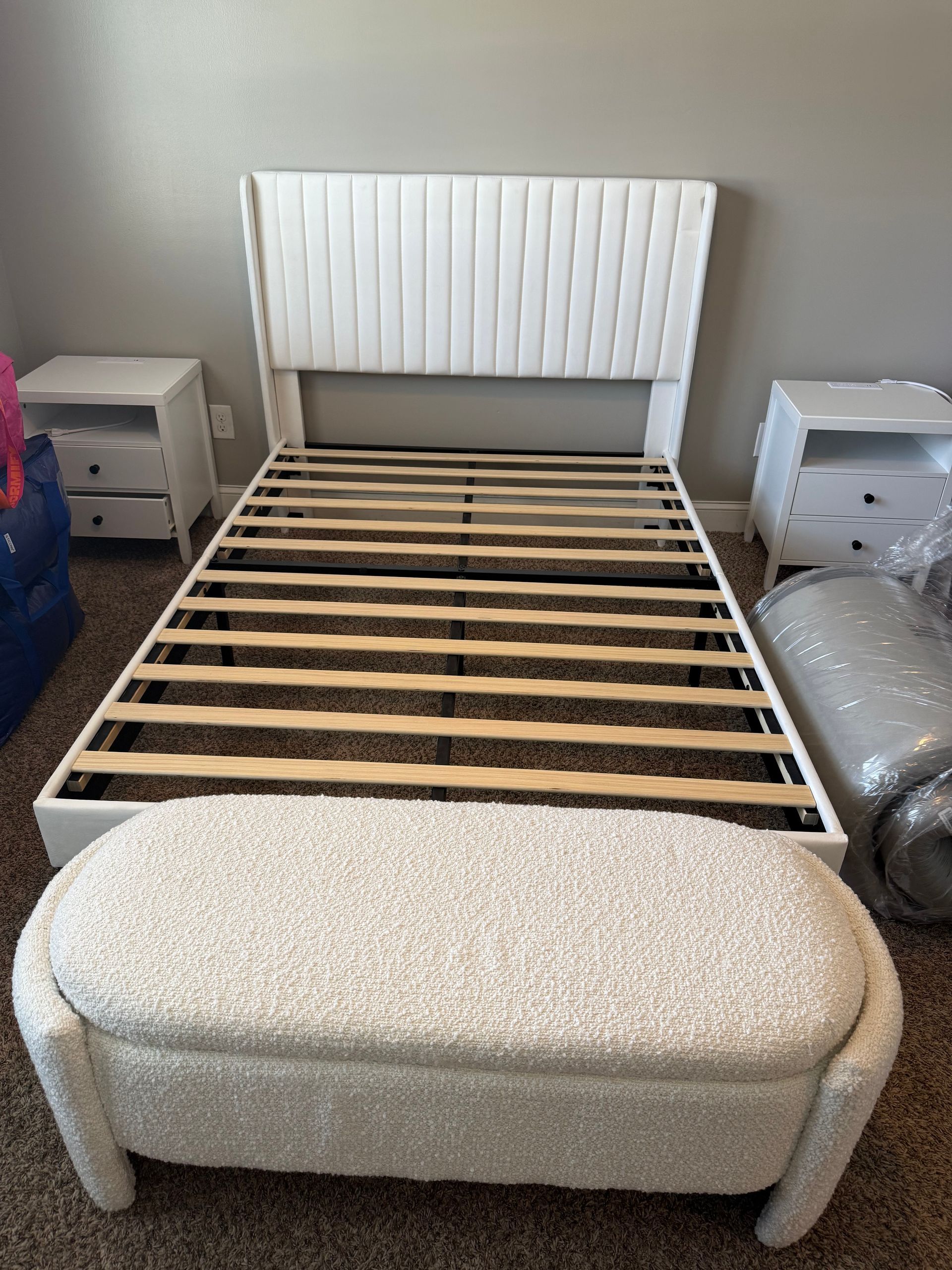 White bed frame with headboard, nightstands, and bench in a bedroom.