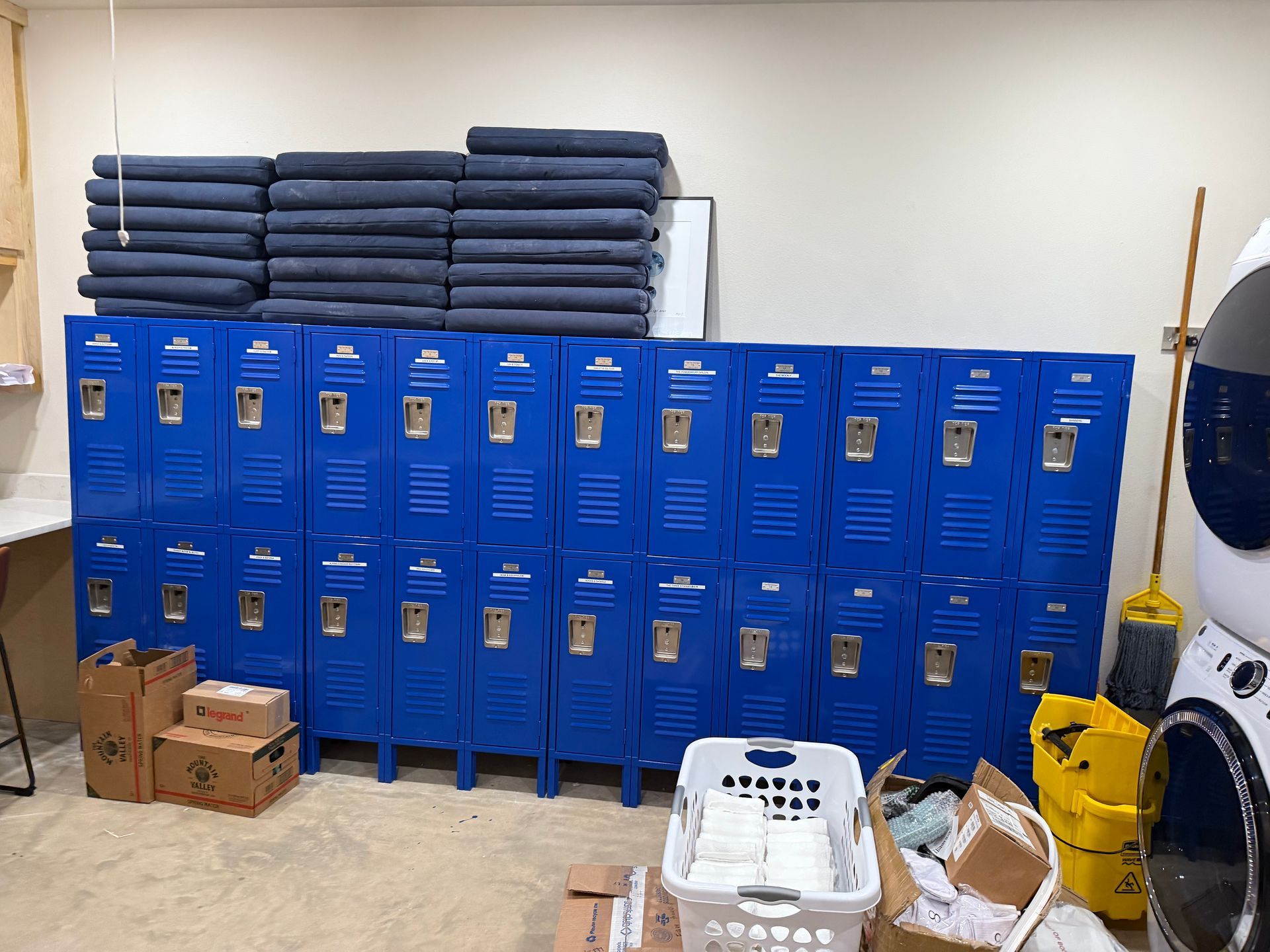 Blue lockers with towels stacked on top, laundry basket, and cardboard boxes.