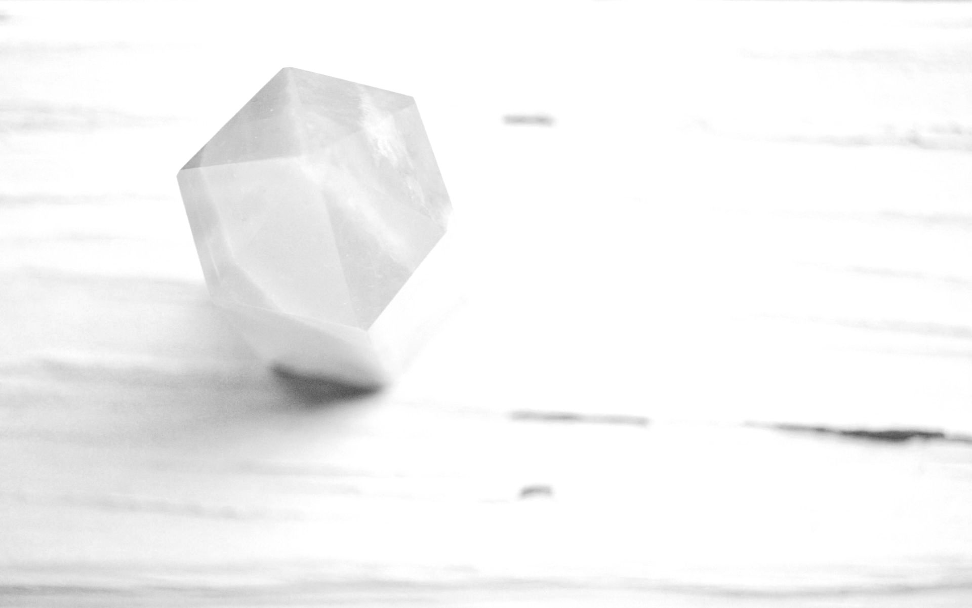 A pink crystal is sitting on a white wooden table.