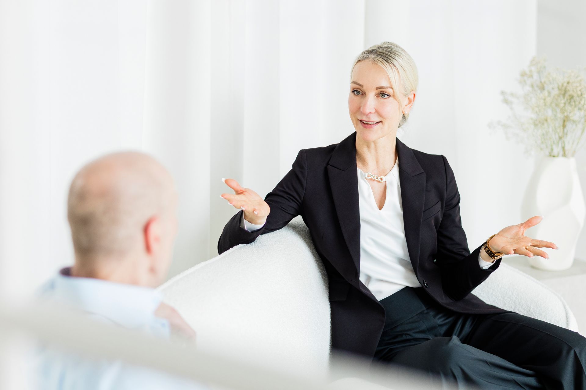 Ein Meeting in einem Büro, bei dem eine Person gestikuliert, während sie sich mit jemandem unterhält, der ihr gegenübersitzt.