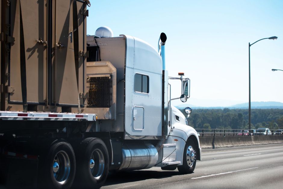 A white semi truck is driving down a highway.