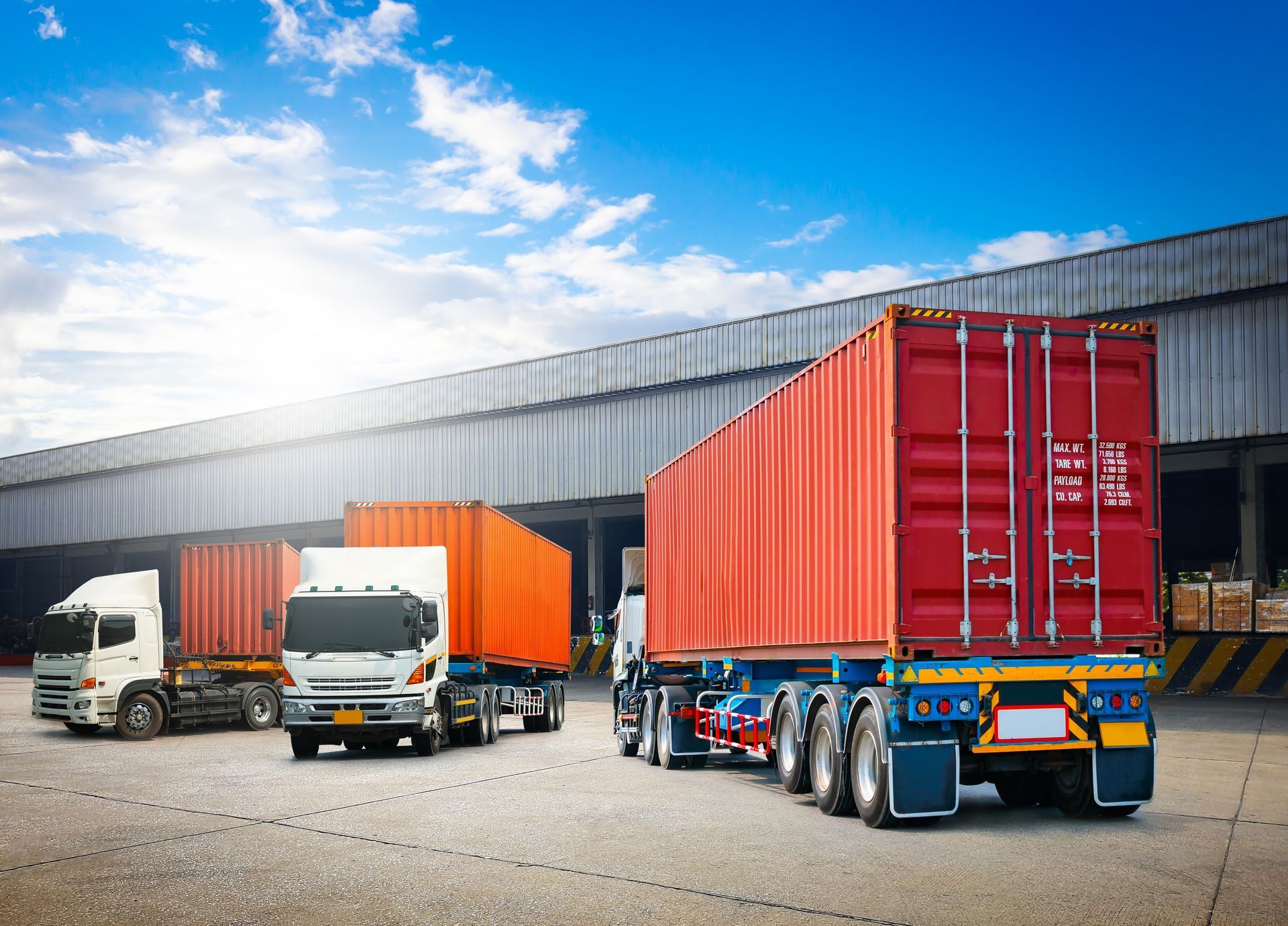 A group of trucks are parked in front of a warehouse.