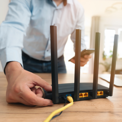 A man is plugging a cable into a router
