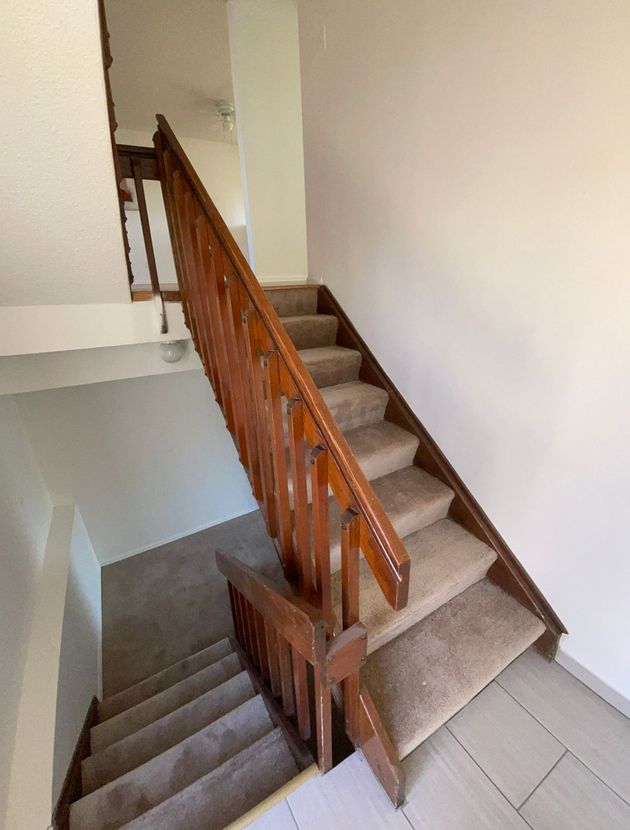 A wooden staircase with carpeted steps and a wooden railing