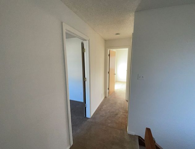 A hallway in a house with a staircase leading to a bedroom.