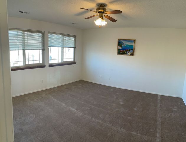 An empty bedroom with a ceiling fan and a picture on the wall.