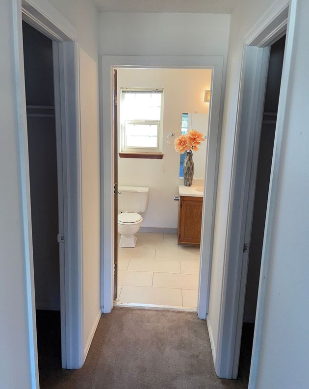 A hallway leading to a bathroom with a toilet and sink