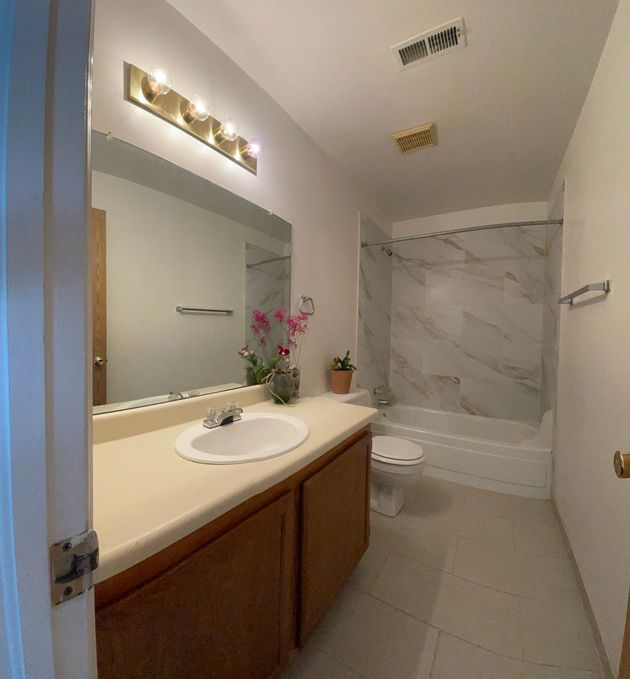 A bathroom with a sink , toilet , tub and mirror.