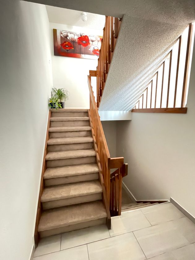 A staircase with a wooden railing and a painting on the wall