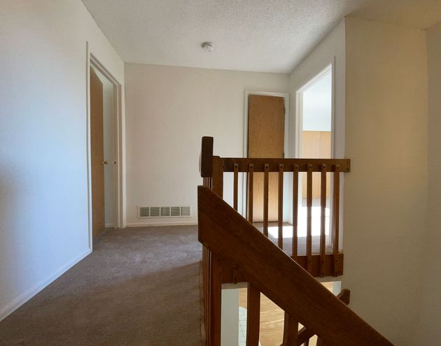 An empty hallway with a wooden railing and stairs