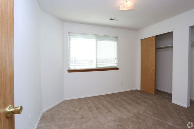 An empty bedroom with a large window and a closet.