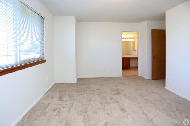 An empty room with a carpeted floor and white walls