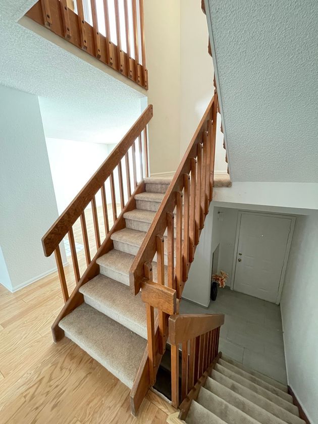 A staircase with a wooden railing and carpeted steps in a house.