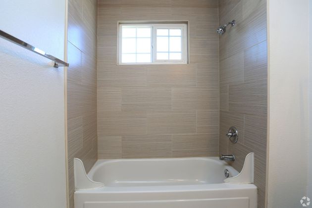 A bathroom with a bathtub and a window.