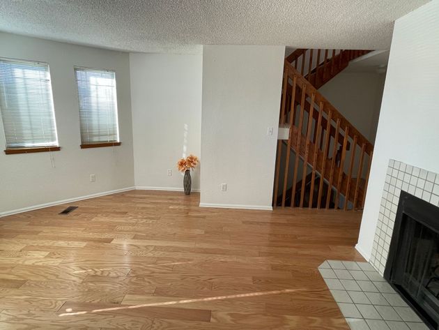 An empty living room with hardwood floors and a fireplace