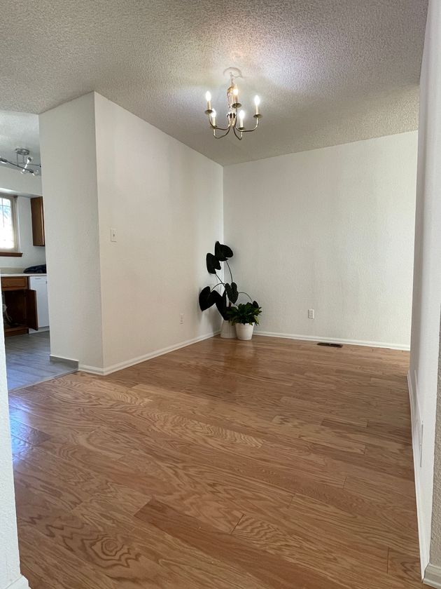 An empty living room with hardwood floors and a chandelier.