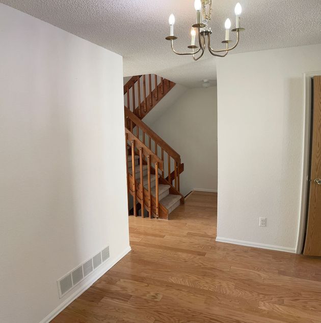 A hallway with a wooden staircase and a chandelier hanging from the ceiling