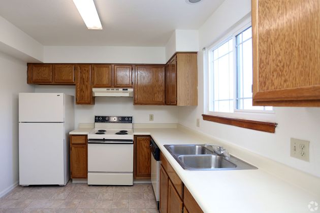 An empty kitchen with wooden cabinets and a white refrigerator