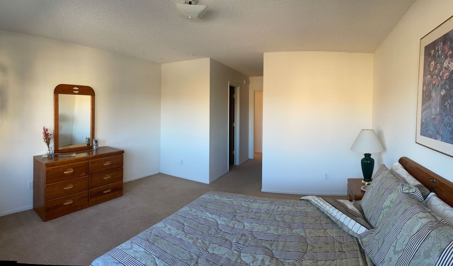 A bedroom with a dresser and a mirror on the wall.