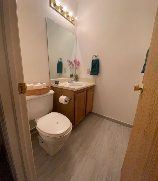 A bathroom with a toilet , sink and mirror.