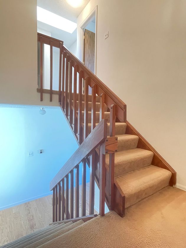 A staircase with a wooden railing and carpeted steps in a house