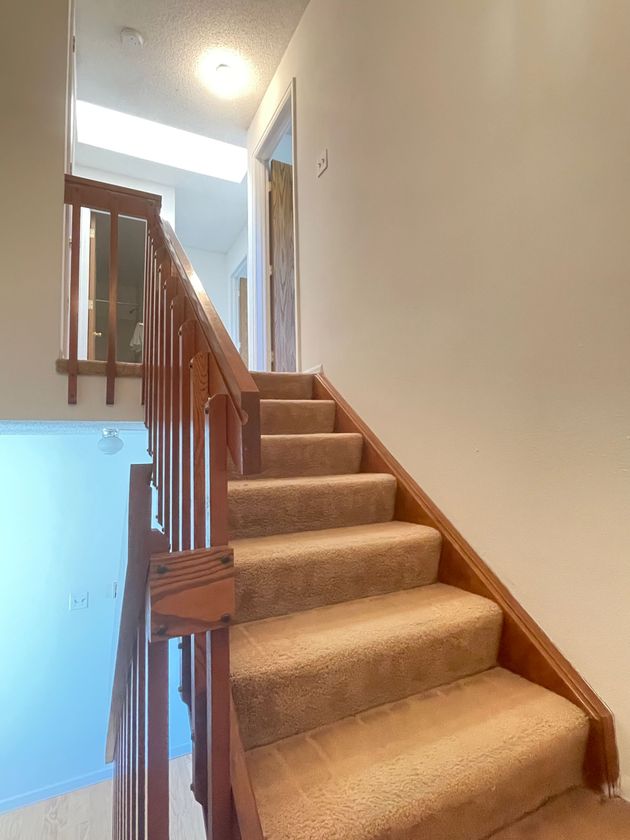 A staircase with a wooden railing and carpeted steps in a house.