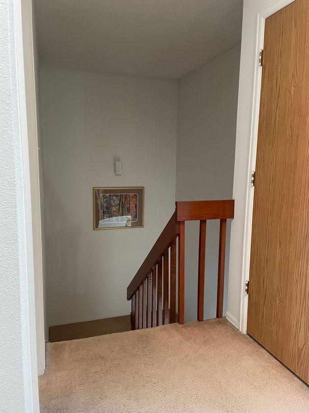 A staircase with a wooden railing and a picture on the wall.