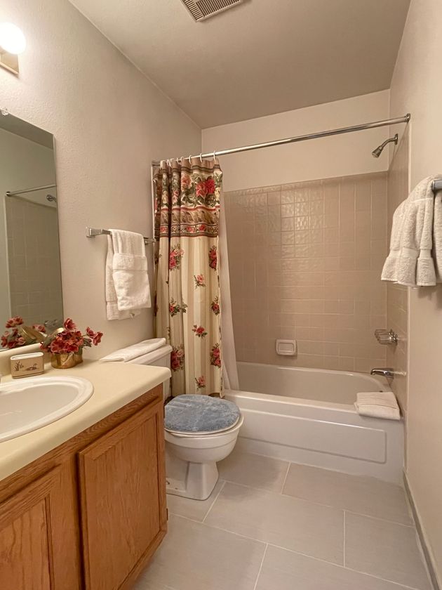 A bathroom with a toilet , sink , bathtub and shower curtain.