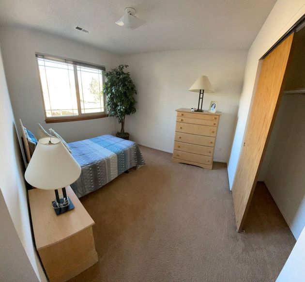 A bedroom with a bed dresser and lamp