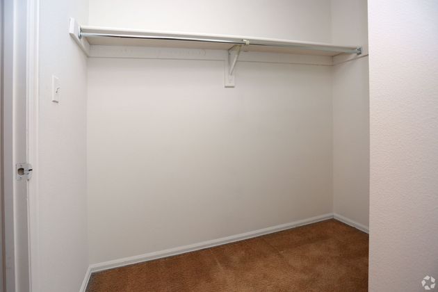 An empty walk in closet with a carpeted floor and shelves.