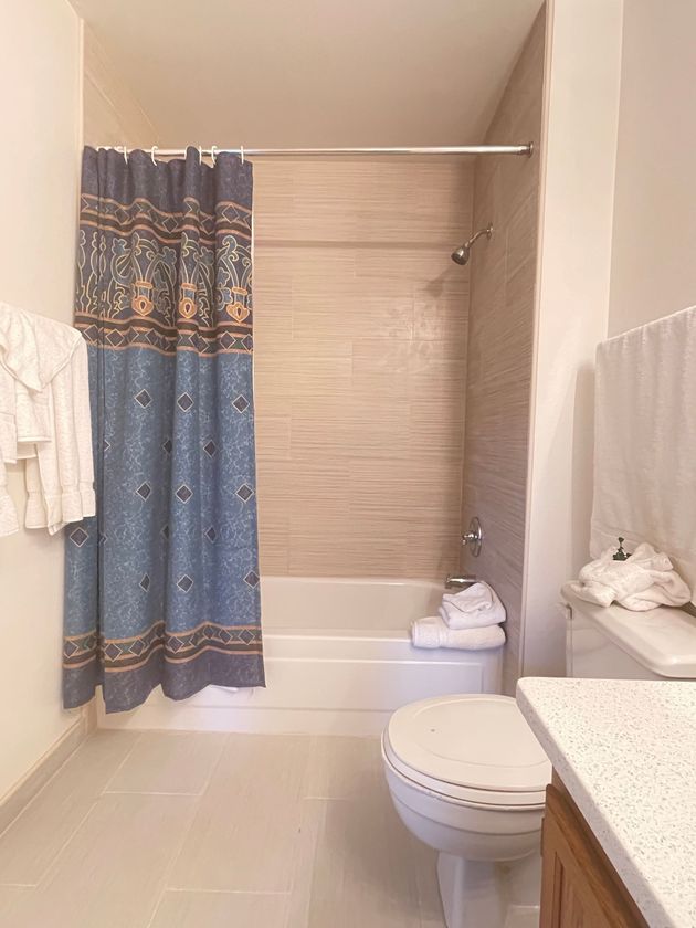 A bathroom with a toilet , sink , bathtub and shower curtain.