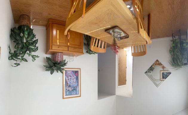 A dining room table and chairs are upside down in a room.