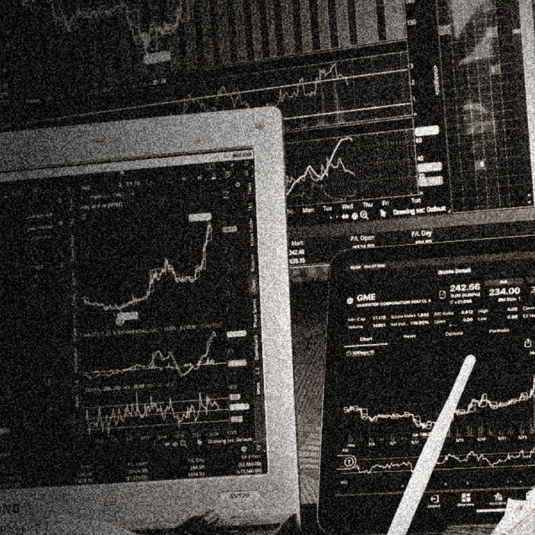 grainy image of a bank of computer screens with graphs depicted on them