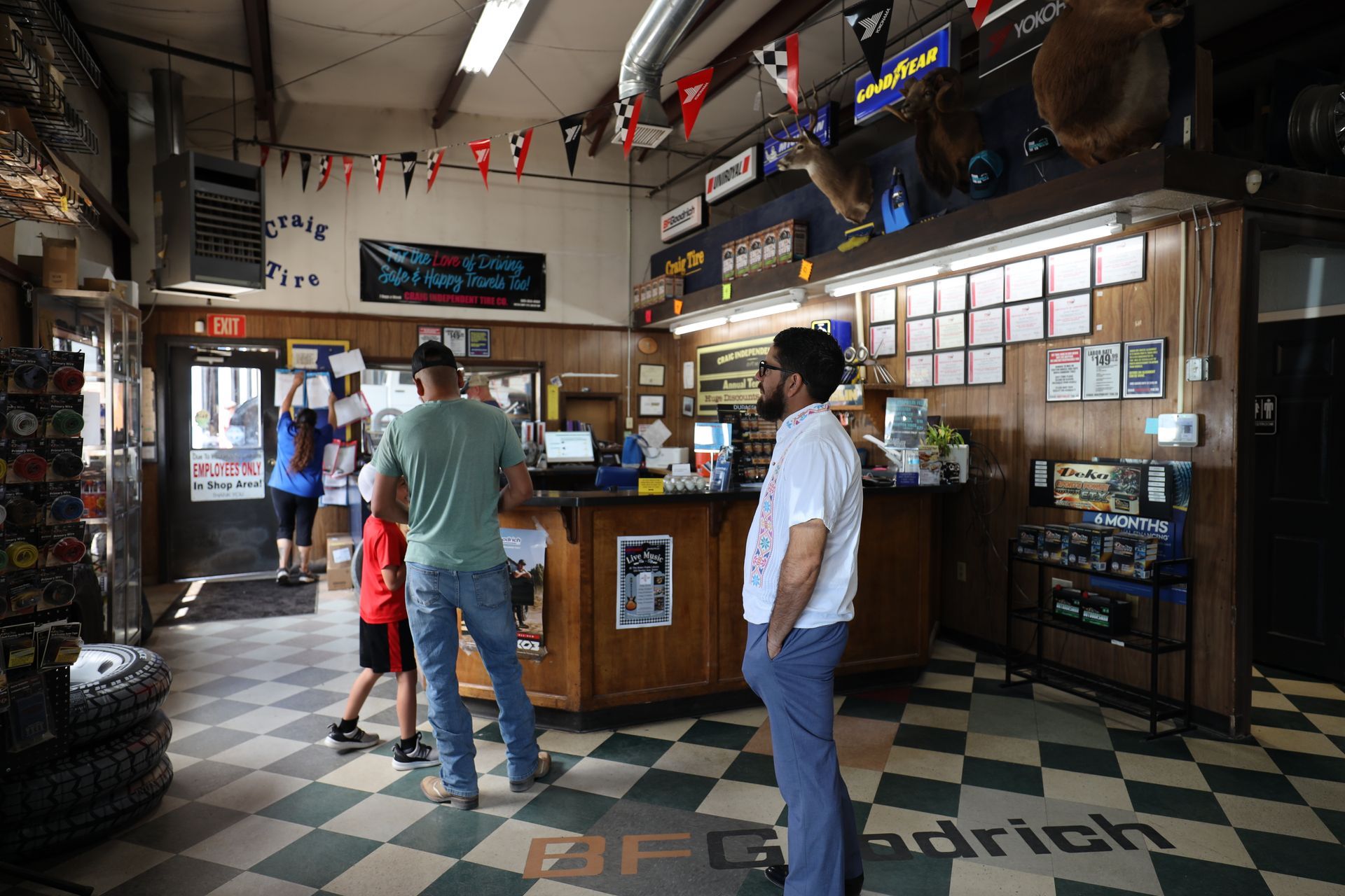 Mechanic with tires and a black truck and silver car | Craig Independent Tire Co.