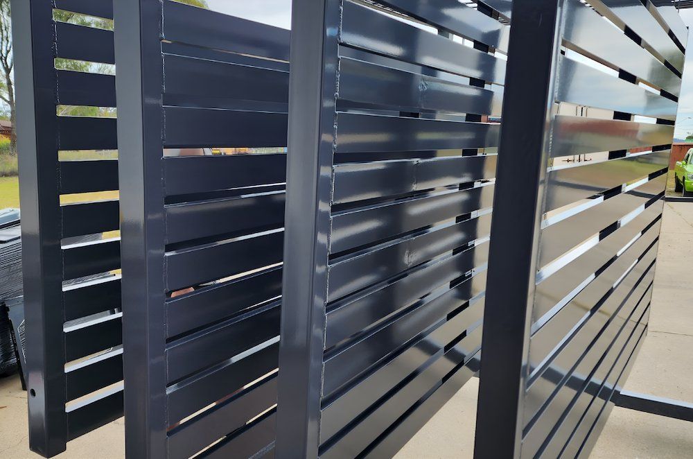 A black metal fence is sitting on the ground — ADK Coatings In Toolooa, QLD