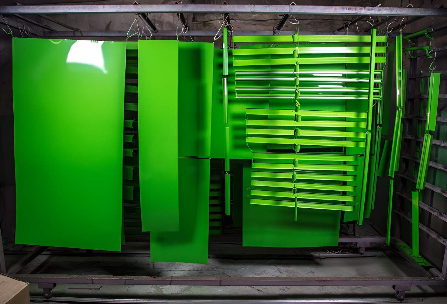 A bunch of green pieces of metal are hanging on a rack — ADK Coatings In Biloela, QLD