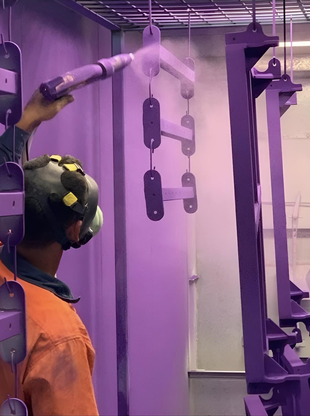 A Man Wearing A Helmet Is Spraying Powder On A Piece Of Metal — ADK Coatings In Toolooa, QLD