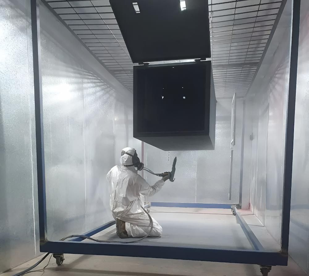 A Man In A Protective Suit Is Kneeling Down In A Room Holding A Tool — ADK Coatings In Toolooa, QLD