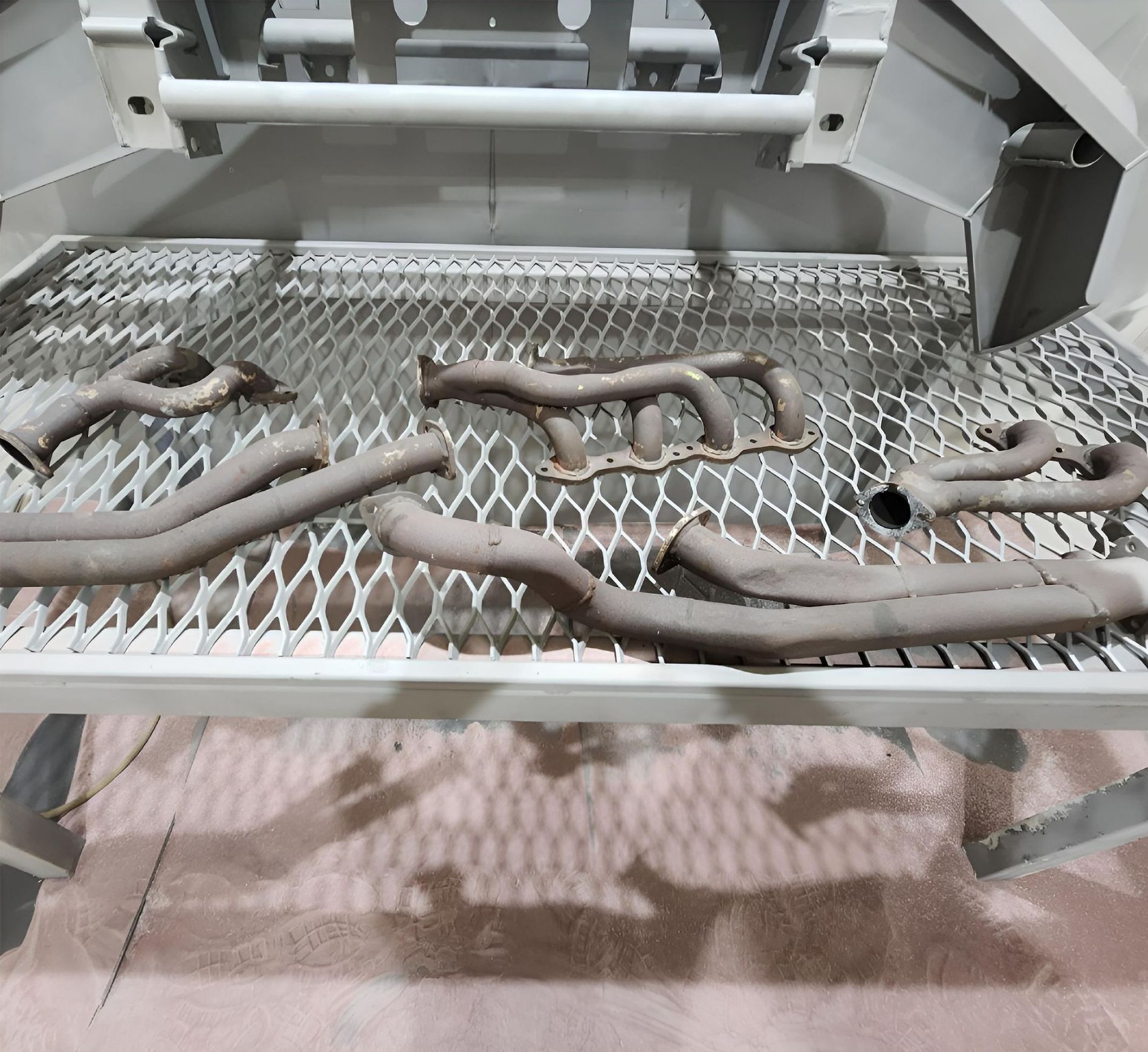 Exhaust pipes are sitting on a metal mesh tray — ADK Coatings In Toolooa, QLD