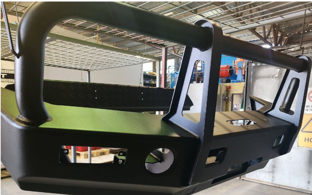 A Black Bumper Is Hanging From The Ceiling Of A Building — ADK Coatings In Boyne Island, QLD